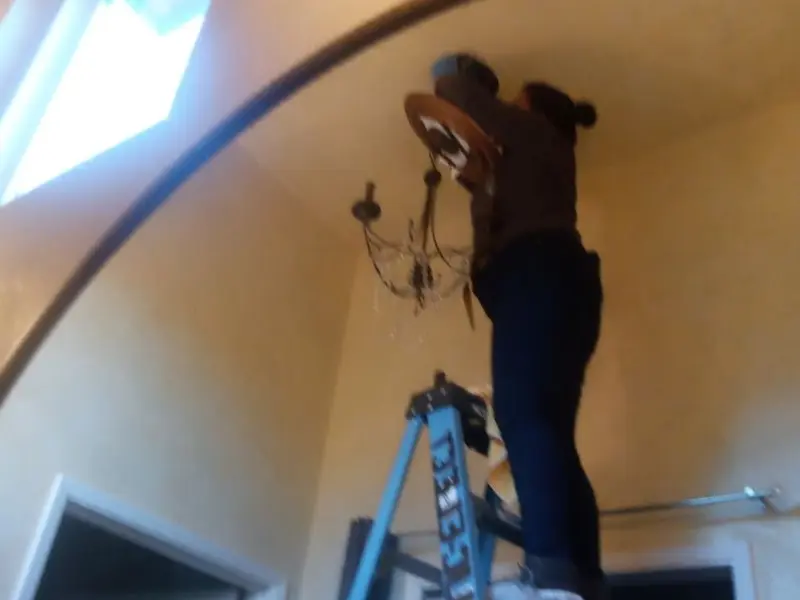 Electrician installing a chandelier in a Portland residence